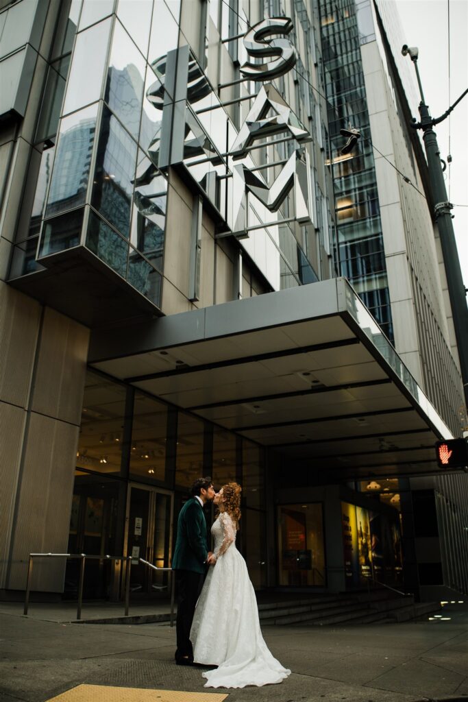 Wedding portraits outside the Seattle Art Museum featuring modern architecture and city surroundings