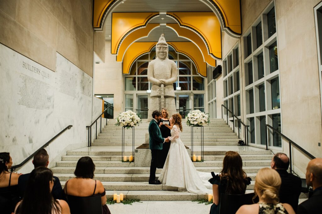 Wedding ceremony at the Seattle Art Museum with guests gathered beneath the museum’s architectural interior