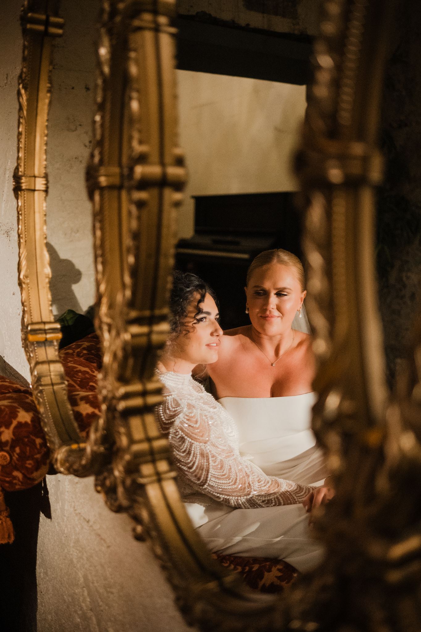 Reflection of Brides in Mirror While Sitting in Lobby of Wedding Venue