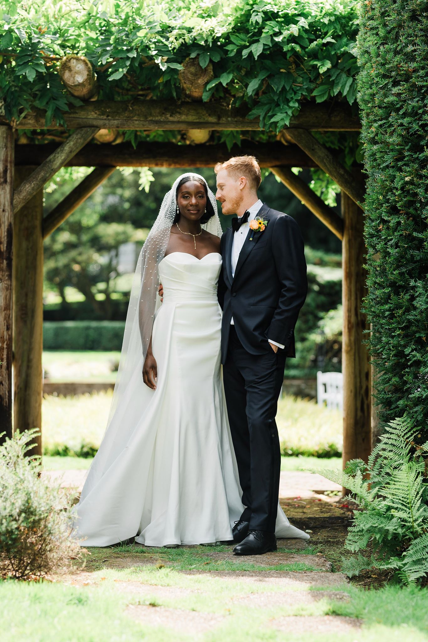 Bride and Groom Pose for Photos in Gardens of Carnation Farms Wedding Venue